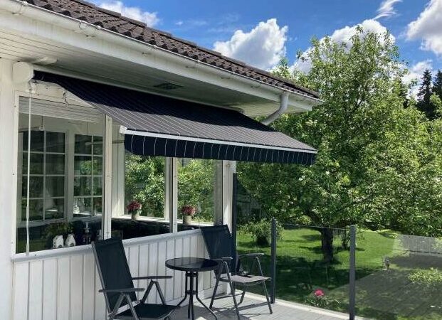 En terrassmarkis med ljusgrå aluminiumkåpa över en terrass