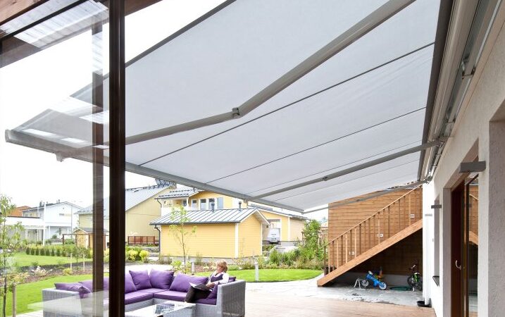 En stor ljus terrassmarkis med underprofil över en stor terrass med utemöbler