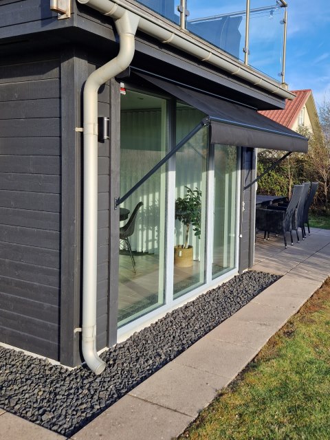 Svart fönstermarkis över ett stort fönsterpart