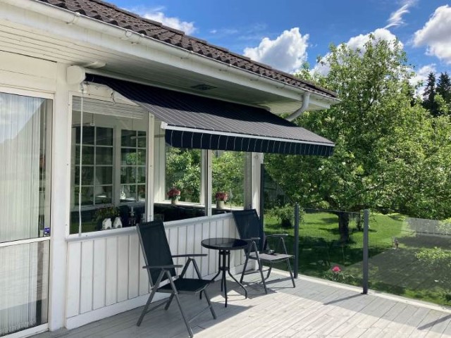 Svart terrassmarkis monterad på villa över en terrass